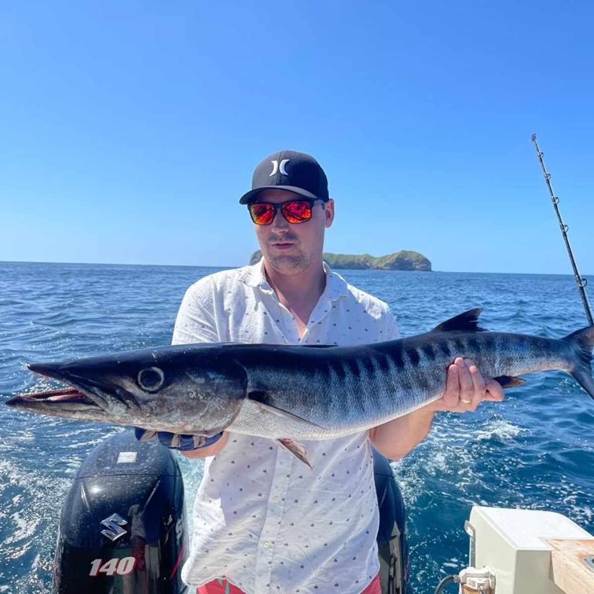 a man holding a fish on a boat in a body of water