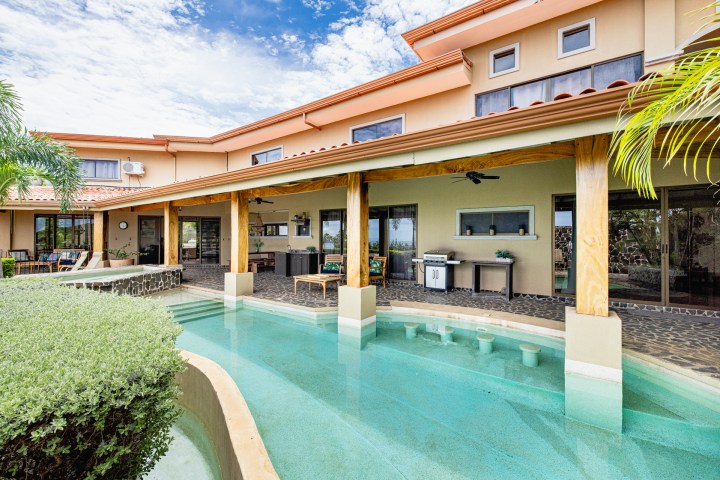 Modern house with pool and patio under a blue sky.