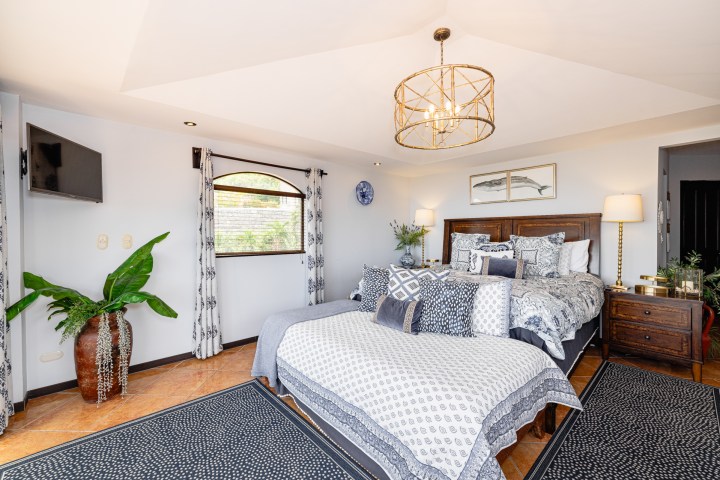 Elegant bedroom with patterned bedding, wooden furniture, and a circular chandelier.