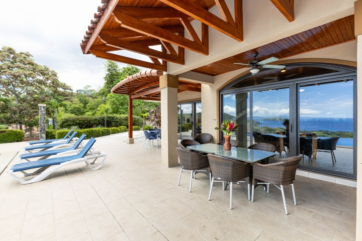 Outdoor patio with dining table, chairs, lounge chairs, and ocean view.