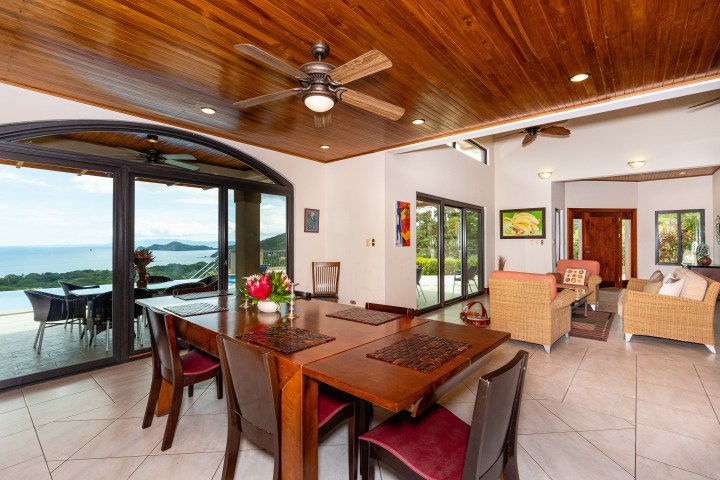 Spacious living and dining area with ocean view, wooden ceiling, and modern furniture.