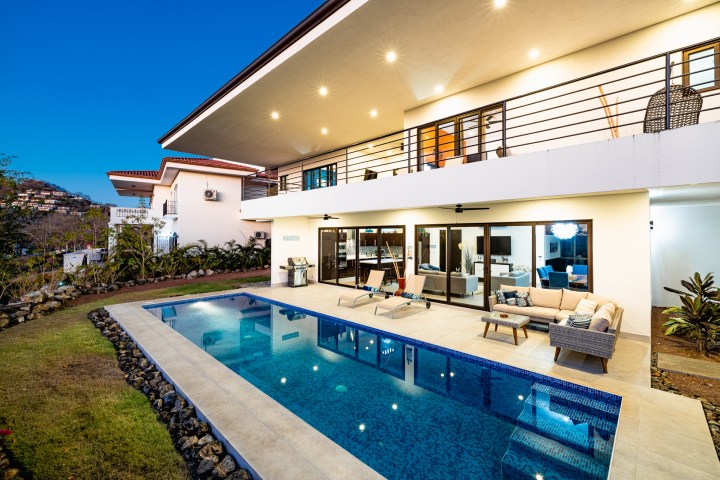 Modern house with pool and patio furniture at dusk.