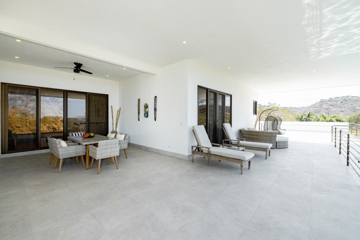 Spacious terrace with lounge chairs, dining table, and mountain view.