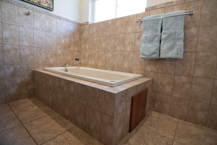 Bathroom with tiled bathtub and two folded towels hanging on a rack.