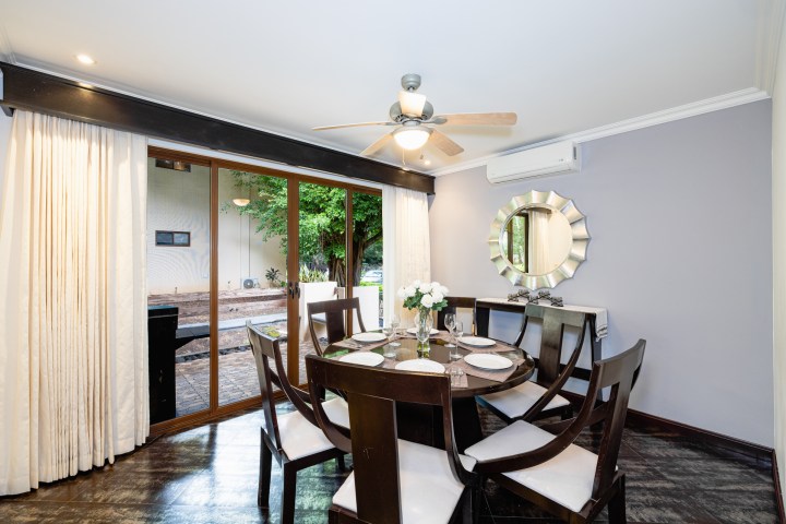 Dining room with round table, six chairs, large mirror, ceiling fan, and sliding glass doors to patio.