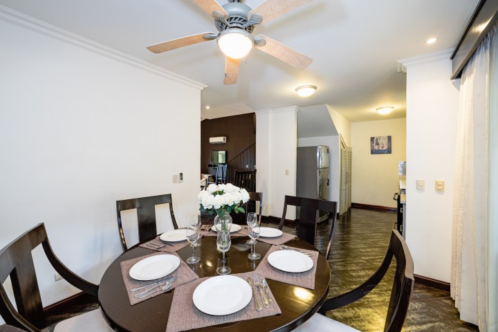 Dining room with round table, set for six, and ceiling fan overhead.