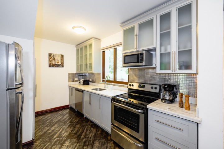 Modern kitchen with stainless steel appliances, white cabinets, and tiled backsplash.