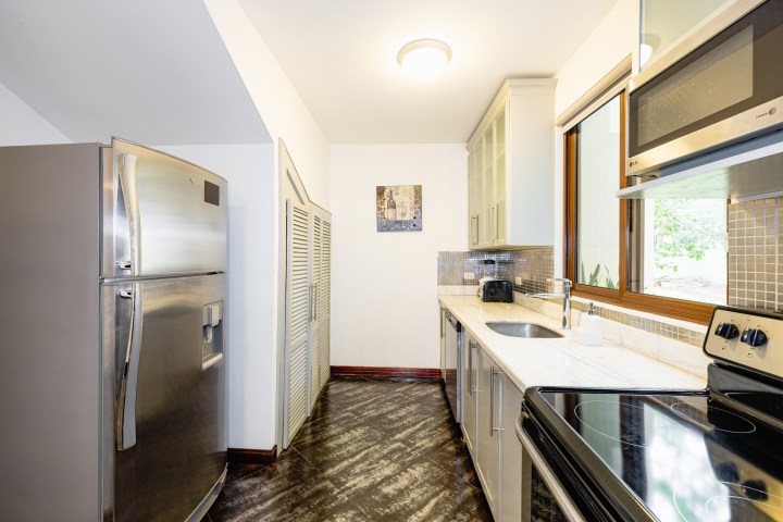 Modern kitchen with stainless steel appliances, white cabinets, and marble countertops.