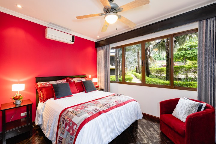 Bedroom with red accents, large window, and a ceiling fan.