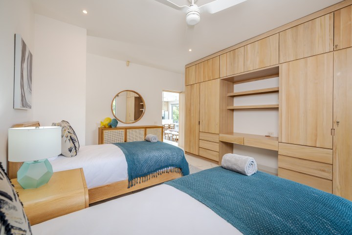 Modern bedroom with two twin beds, blue blankets, and wooden cabinets.