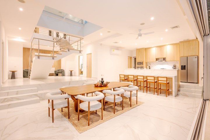 Modern open-plan kitchen and dining area with wooden furniture and tile flooring.