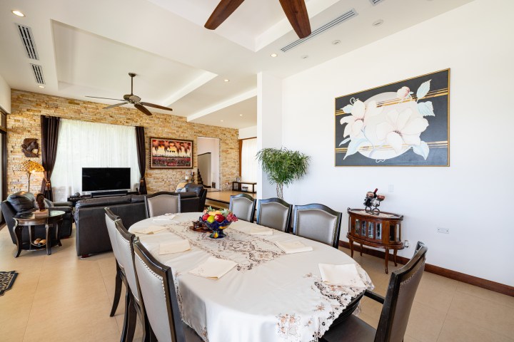 Spacious living room with dining table, floral art, sofa, TV, and ceiling fans.