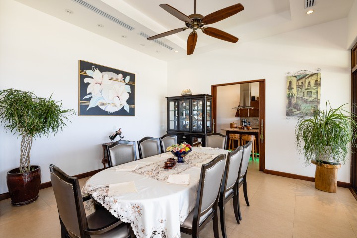 Elegant dining room with a table for eight, ceiling fan, artwork, and plants.