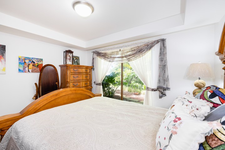 Cozy bedroom with wooden furniture and large window view of garden.