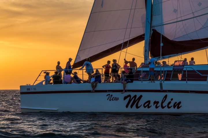 People on a sailboat named New Marlin at sunset.