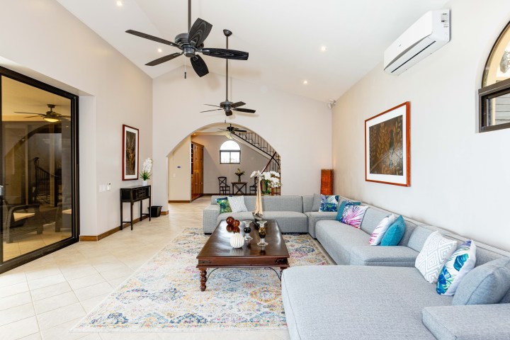 Modern living room with gray sectional sofa, ceiling fans, and art on walls.