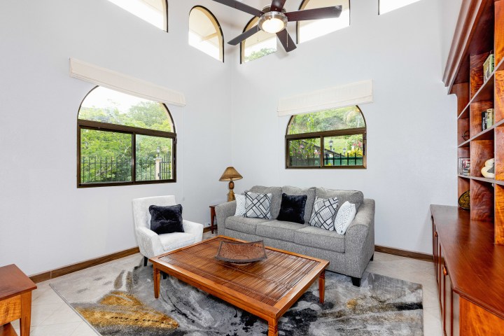 Living room with gray sofa, white armchair, wooden coffee table, and large windows.