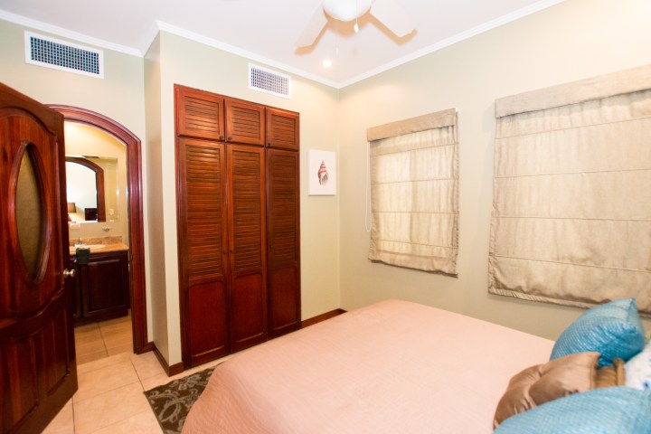 Bedroom with wooden closet, beige walls, and arched doorway to a bathroom.