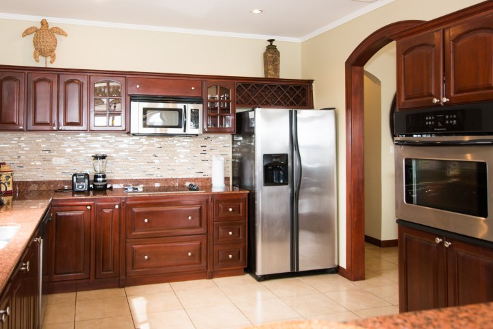 Modern kitchen with dark wood cabinets, stainless steel appliances, and a tiled backsplash.
