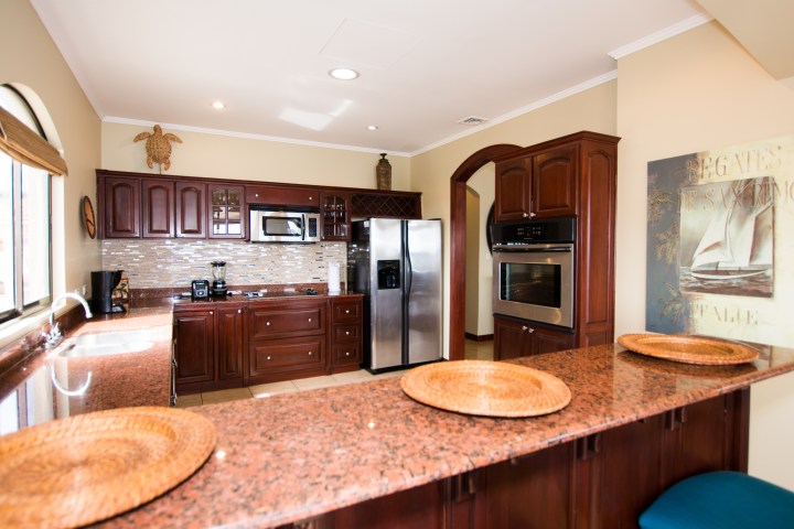 Modern kitchen with dark wood cabinets, stainless steel appliances, and granite countertops.