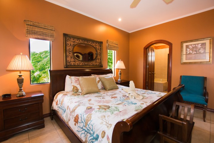 Elegant bedroom with orange walls, wooden furnishings, and a large bed.