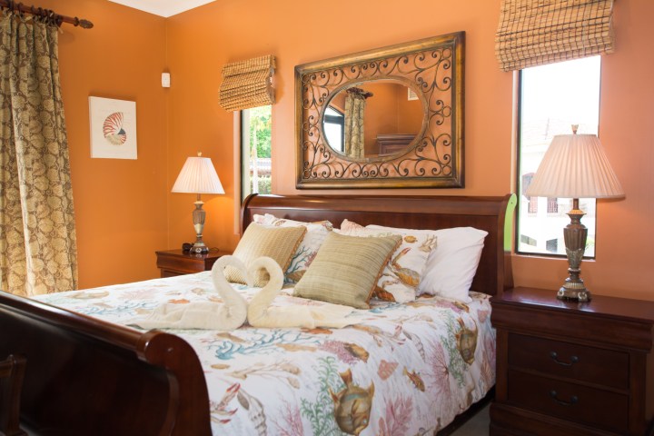 Cozy bedroom with orange walls, seashell bedding, and swan towels on the bed.