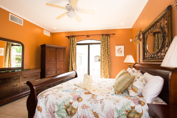 Warm bedroom with sea-themed bedding, wooden furniture, and mirrored dresser.