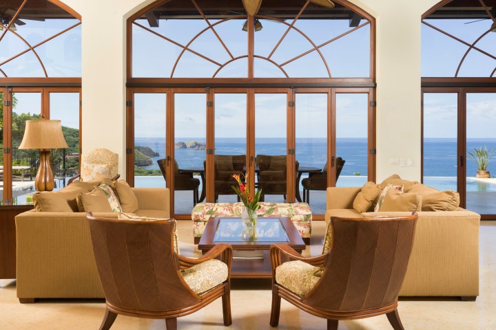 Luxurious living room with large windows overlooking an ocean view and elegant furniture.