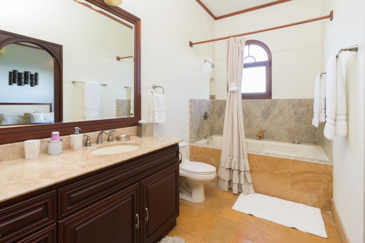 Bathroom with a sink, mirror, toilet, and bathtub with shower curtain.