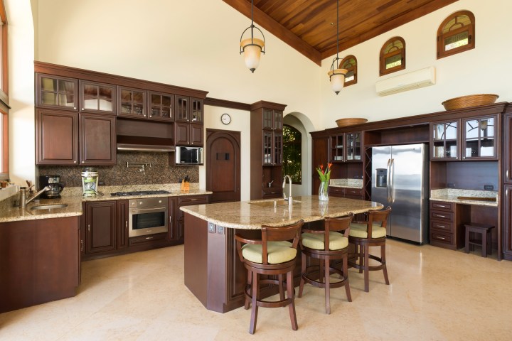 Spacious kitchen with wooden cabinets, island, and stainless steel appliances under vaulted ceiling.