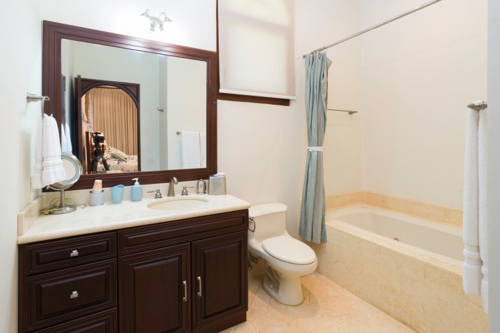 Bathroom with wood vanity, sink, toilet, and bathtub with curtain.