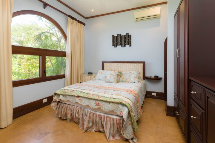 Bedroom with a window, bed with floral bedding, wooden wardrobe, and wall art.