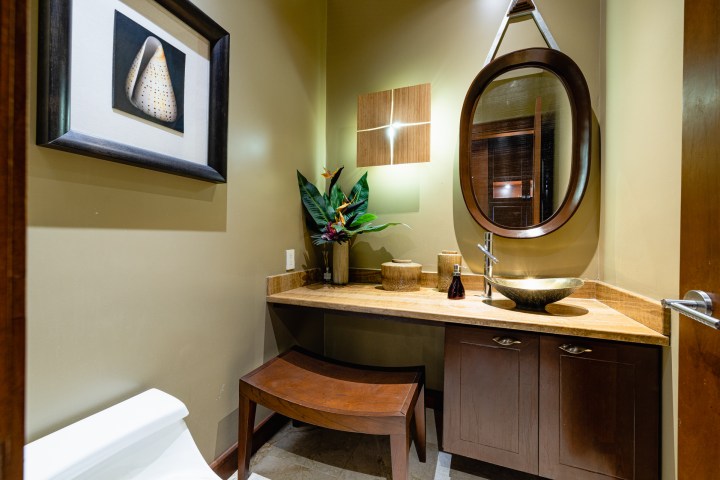 Modern bathroom with oval mirror, vessel sink, and framed artwork on wall.