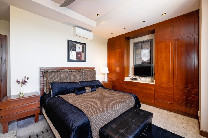Modern bedroom with brown bedding, wooden furniture, wall art, and a small TV on cabinet.