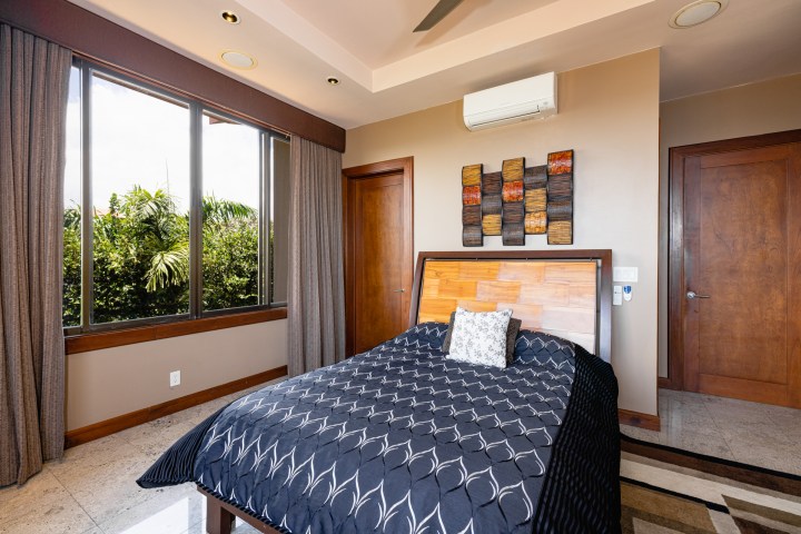 Bedroom with a large window, double bed, and abstract wall art above wooden headboard.