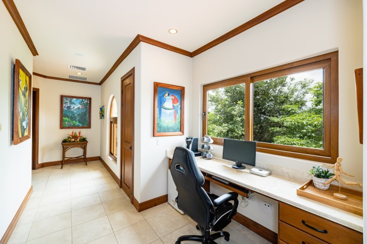 Home office with desk, chair, computer, and large window with a view of trees.