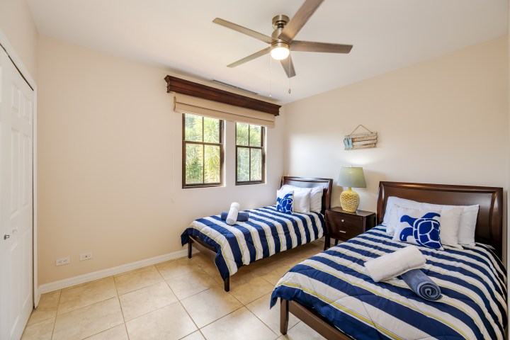 Room with two striped twin beds, a ceiling fan, and a window.