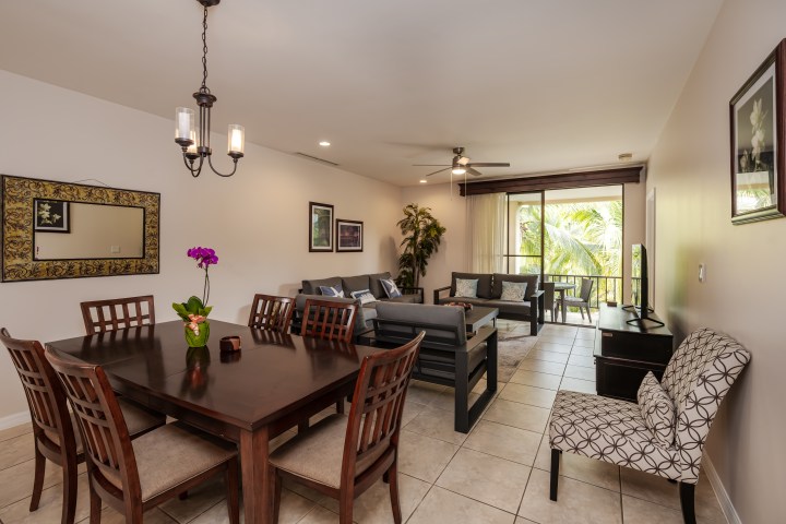 Dining and living area with wooden furniture, wall decor, and a view of greenery through sliding doors.