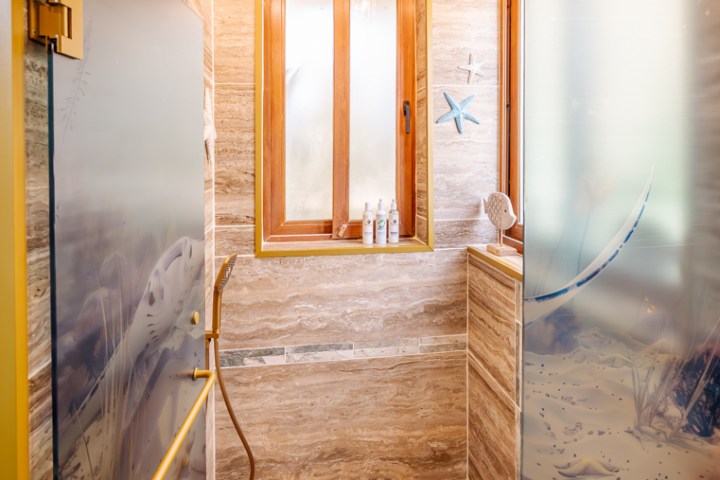 Wood-themed shower with frosted glass, starfish decor, and ceiling showerhead.