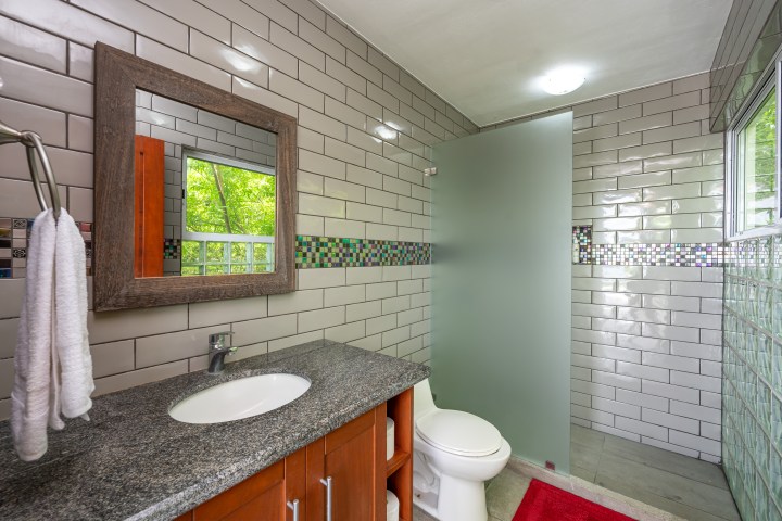 Modern bathroom with glass shower, sink, toilet, and tiled walls.