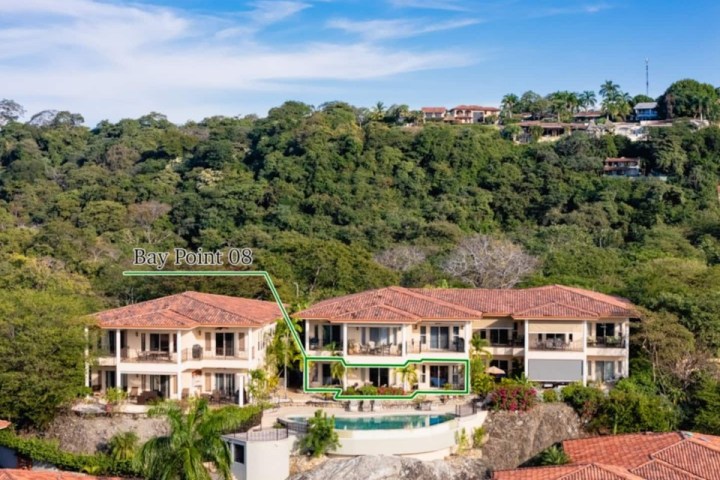 Three luxury villas with red roofs in a lush green hillside setting.