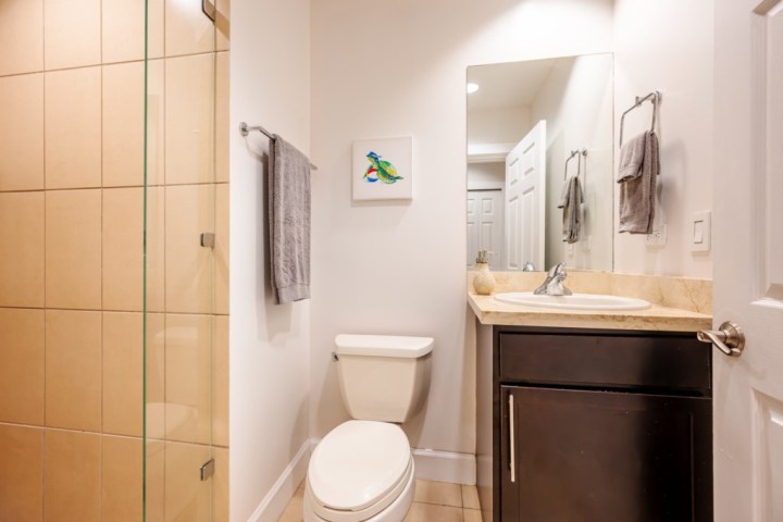 Modern bathroom with a toilet, sink, mirror, and shower on the left.