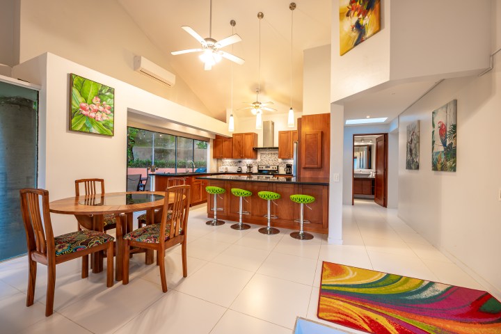Modern kitchen and dining area with colorful decor and artwork, featuring a wooden dining table and bar stools.