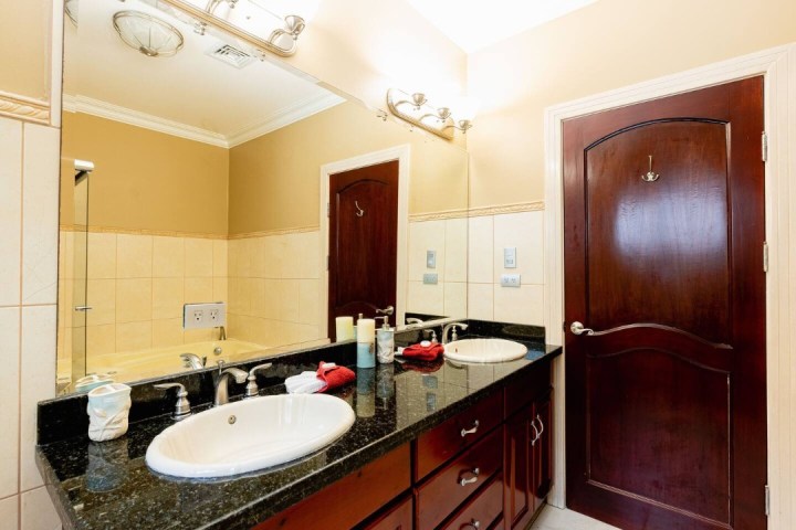 Bathroom with double sinks, granite countertop, and wooden door.