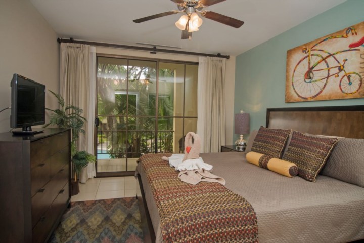 Bedroom with a bed, a bicycle painting, TV, and glass doors leading outside.