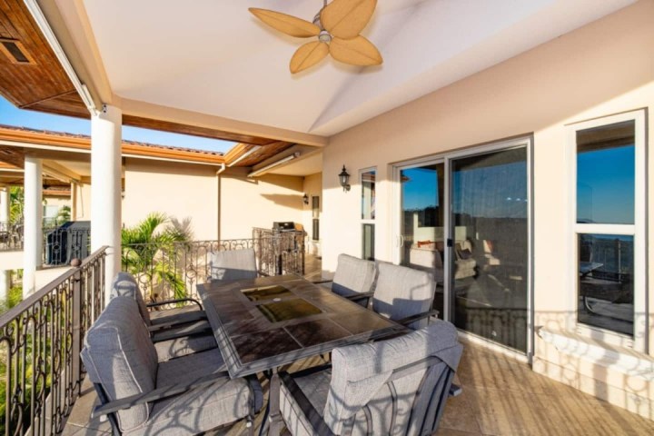 Outdoor patio with a dining set, ceiling fan, and sliding glass doors.