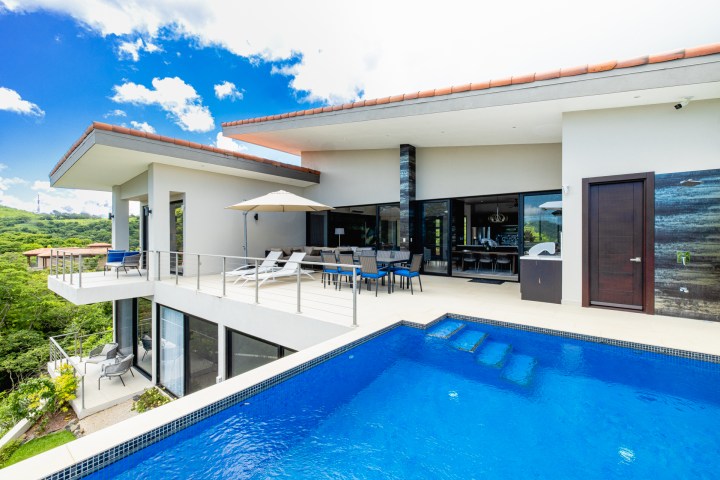 Modern villa with pool and patio on a sunny day.
