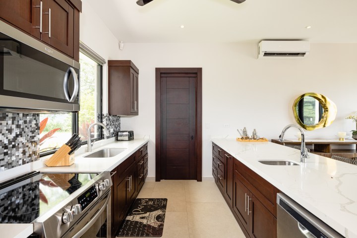 Modern kitchen with dark wood cabinets, white countertops, and stainless steel appliances.