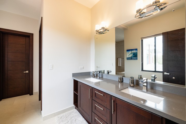 Modern bathroom with double sink, large mirror, and wooden cabinets.