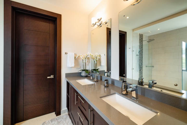 Modern bathroom with dark wood accents, double sink vanity, and a large mirror.